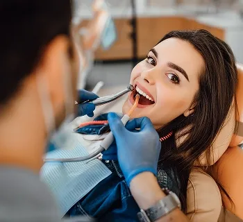 Patient receiving dental care with a dentist using tools, showcasing a comfortable dental experience at Sunshine Smiles Dental & Braces.